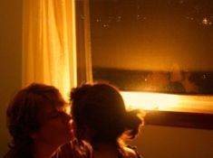 two people are looking out the window at night