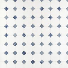 a white and blue tiled wall with small flowers on the bottom half, in an irregular pattern