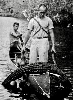 an old photo of two men in a boat with alligators on the front and back