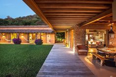 an outdoor patio with chairs and tables next to a covered area at night, surrounded by lush greenery