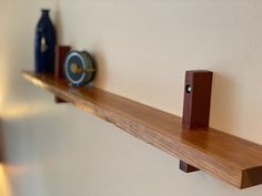 a shelf with two speakers on it next to a wall mounted clock and vases