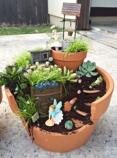 a potted planter filled with plants and fairy figurines on the ground