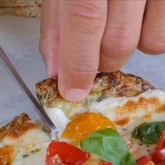 a person cutting into a pizza with a knife and some toppings on the top