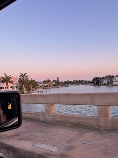 a view from inside a car looking out at the water and palm trees in the distance