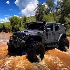 a black jeep driving through some muddy water