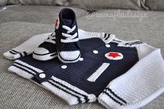 a knitted sweater and pair of sneakers on top of a bed