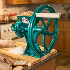 a large green machine on top of a wooden counter next to bread and other items