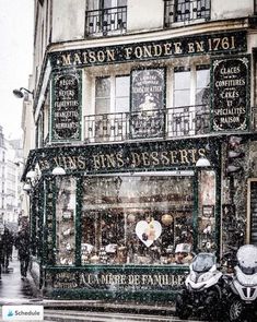 people walking down the street in front of a store on a snowy day with snow falling