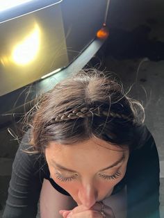 a woman with her hand on her face in front of a car's hood