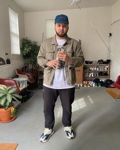 a man standing in a room holding a cell phone and looking at the camera with one hand