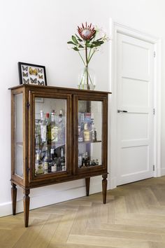 a vase with flowers on top of a wooden cabinet