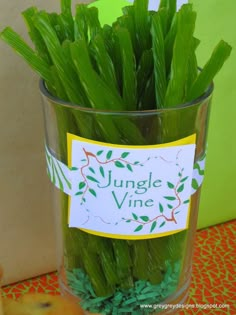 a glass filled with lots of green plants on top of a table next to a sign that reads safari or jungle birthday party ideas?