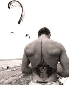 a man riding on the back of a motorcycle down a beach covered in kites