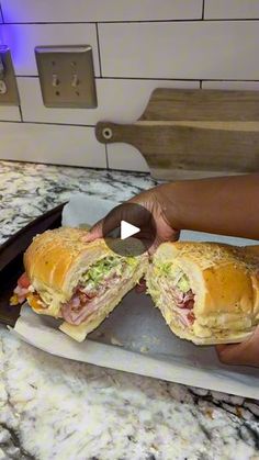 a person holding a sandwich in their hand on top of a counter next to a knife