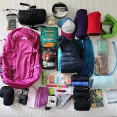 the contents of a backpack laid out on a bed