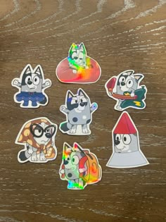 six stickers with different cartoon characters on them sitting on top of a wooden table