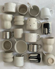 there are many different cups and saucers on the table together, including one that is white