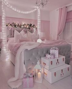 a bedroom decorated in pink and white with presents on the bed, lights around the headboard