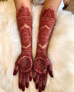 a woman's hands with henna tattoos on them sitting on top of a white rug