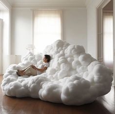 a woman sitting on top of a cloud like bed