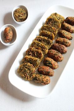 a white plate topped with meatballs next to two small bowls filled with sauces