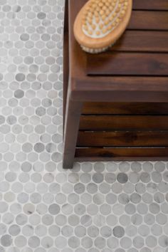 a wooden bench with a brush on top of it in front of a tiled floor