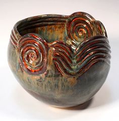 a brown and green bowl with swirl designs on it