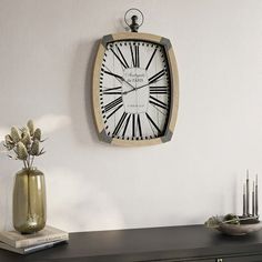 a clock hanging on the wall next to a vase with flowers