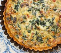 a quiche with spinach, cheese and other toppings in a pie dish