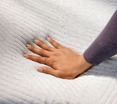 a woman's hand resting on top of a mattress