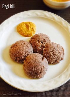 three cookies on a white plate next to some oranges