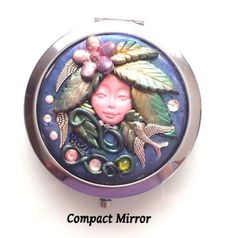 a compact mirror with an image of a woman's face and leaves on it