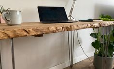 a laptop computer sitting on top of a wooden table next to a potted plant