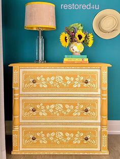 a yellow dresser with sunflowers and a hat on top