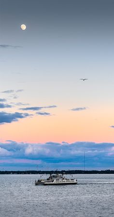 a boat floating on top of a large body of water under a sky filled with clouds