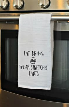 a tea towel hanging on an oven door saying eat drink and wear stretchy pants