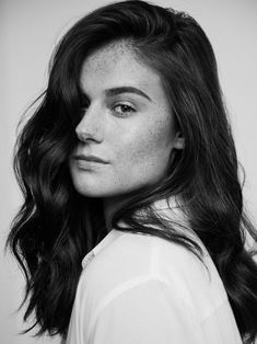 a black and white photo of a woman with freckles on her hair looking at the camera