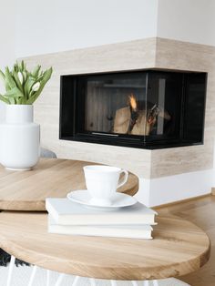 a coffee table with a cup and saucer on it, next to a fireplace