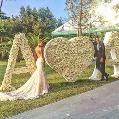 a bride and groom standing in front of letters made out of flowers