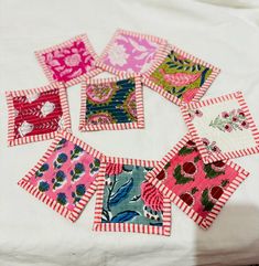 nine patchwork squares are arranged on a white tablecloth with pink and green designs