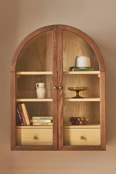 an arched wooden shelf with books and vases