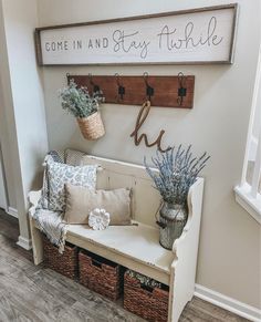 a bench with baskets and flowers on it in front of a sign that says come in and stay fishie