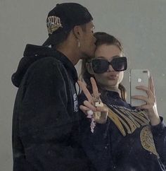 a man and woman standing next to each other holding up their fingers in front of a mirror