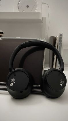 two headphones sitting next to each other on top of a white table with an electronic device in the background