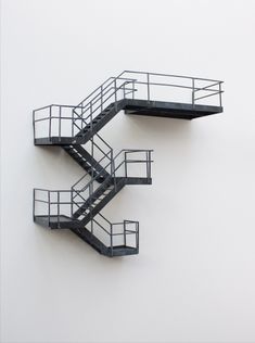 three metal staircases on the side of a white wall with no people in them