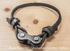 a close up of a leather bracelet on a wooden surface with the text fixe bracet - unchained leather edition