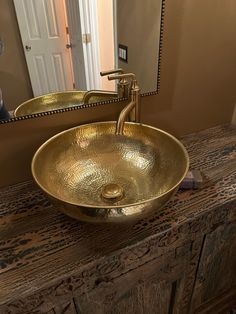 a bathroom sink sitting under a mirror next to a wooden counter