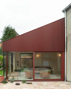 a red building with large glass windows on the front and side walls that have sliding doors open to let in lots of light