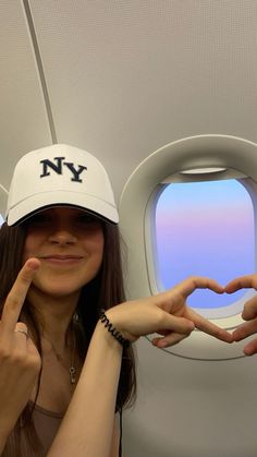 a woman with her hands in the shape of a heart and new york written on her hat