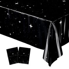 a black tablecloth with white stars on it and two matching napkins to the side